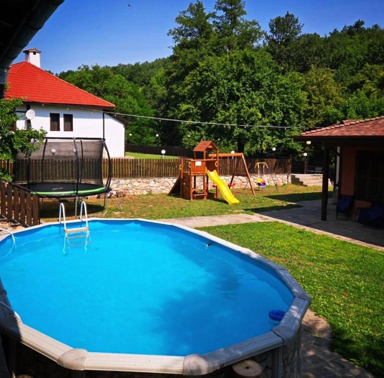 a swimming pool in a yard with a playground at Къща за гости Вила Чифлици in Chiflik