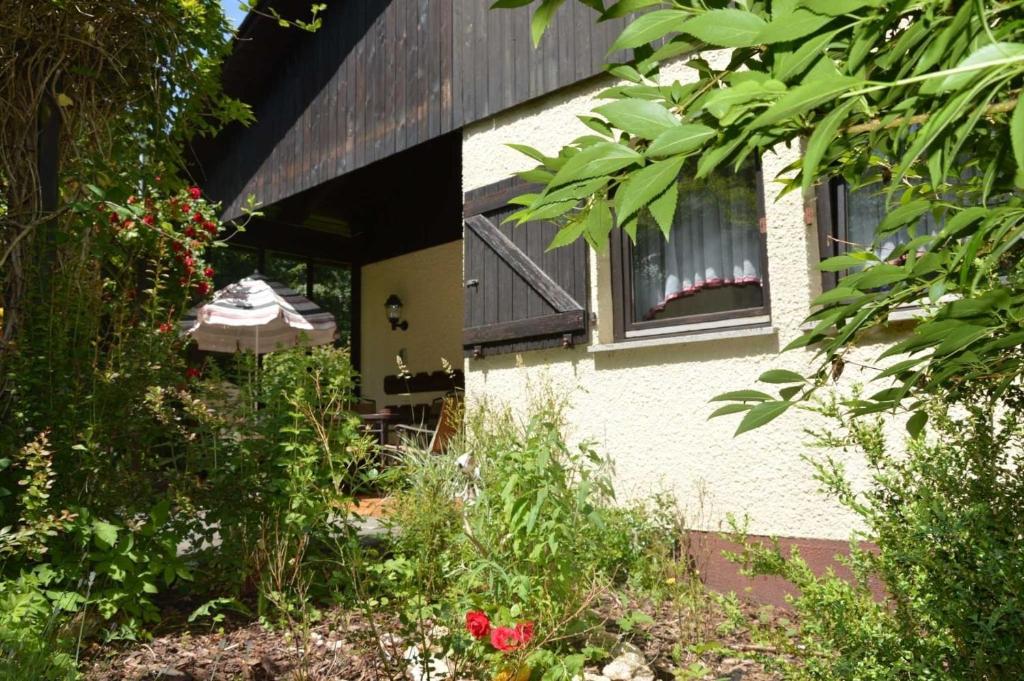 a house with a garden with flowers and an umbrella at Haus Blumengarten in Thalfang