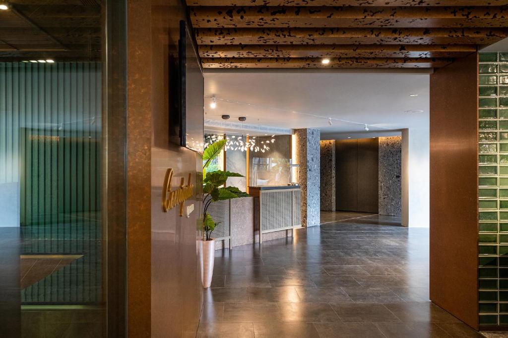 A warmly lit lobby entrance combines a plant, textured finishes, and a visible reception area.