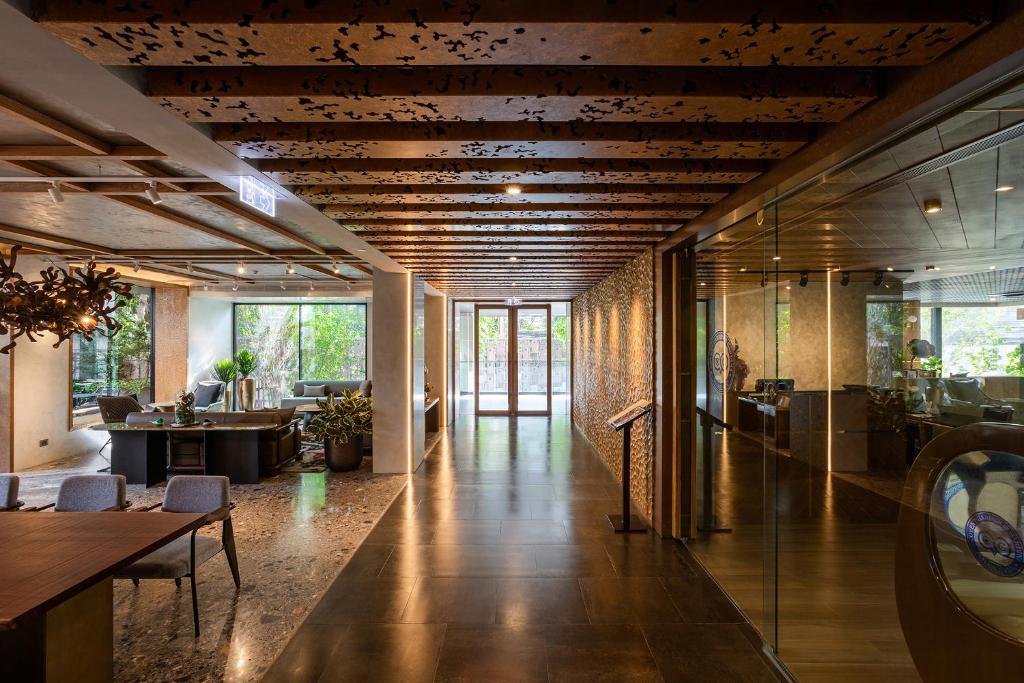 A long lobby corridor leads to glass doors, with seating and a reception zone along the sides.