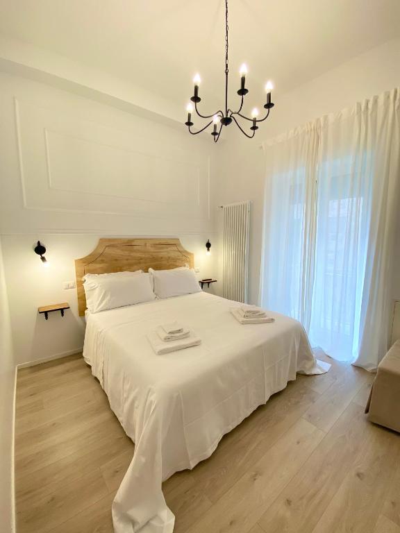 a bedroom with a large white bed with a chandelier at Il Re degli Scalzi in Matera