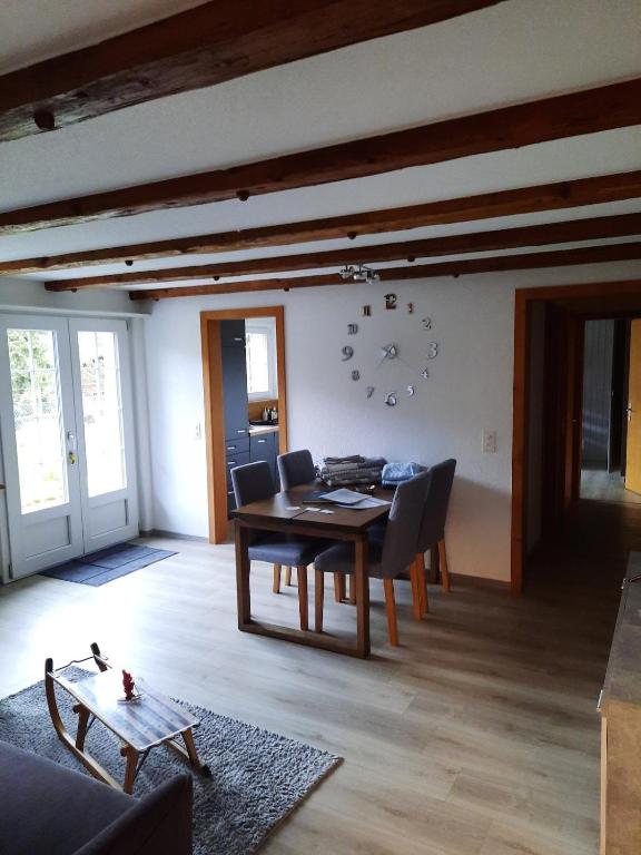 a dining room with a table and chairs and a clock on the wall at Appartement confortable avec terrasse in Zweisimmen