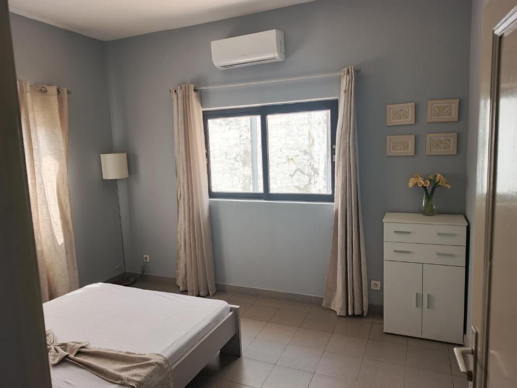 a bedroom with a bed and a window and a dresser at B&B DEGNON Appart in Cotonou