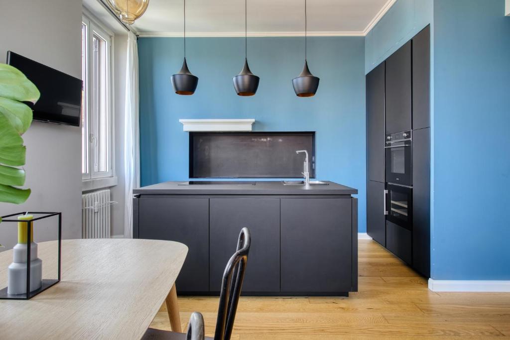una cucina con tavolo e parete blu di Design & Dine a Milano