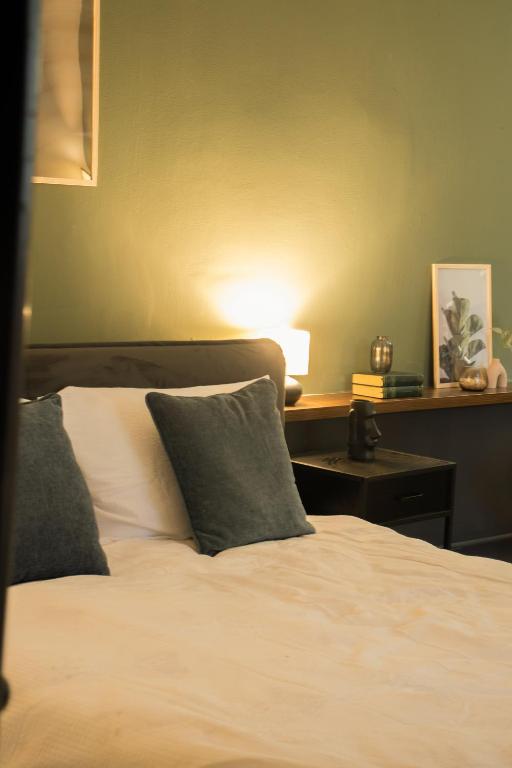 a bed with two pillows and a table with a lamp at Olive Central in Craiova