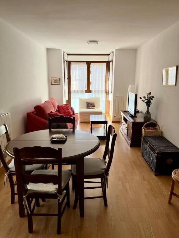 a living room with a table and chairs and a couch at Apartamento Alma centro Biescas l WIFI l Parking in Biescas