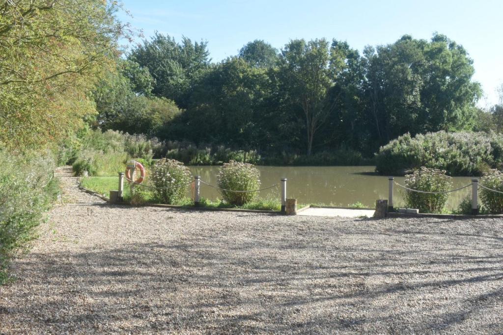 a park with a fence next to a body of water at Swallow cottage in Louth