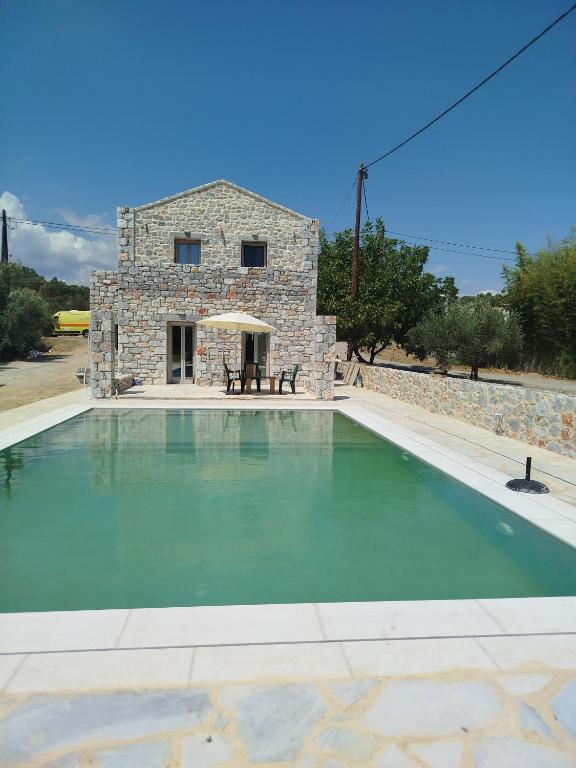 a large swimming pool in front of a stone house at Anastasakos villas in Mavrovouni