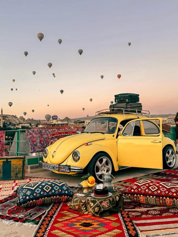 a yellow car with hot air balloons in the sky at Underground Cave Suites Hotel in Göreme
