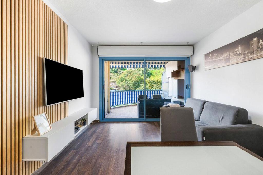 ein Wohnzimmer mit Flachbildfernseher und Couch in der Unterkunft Le Virgil - Piscine - Parking Privé - Calme Wifi in Menton