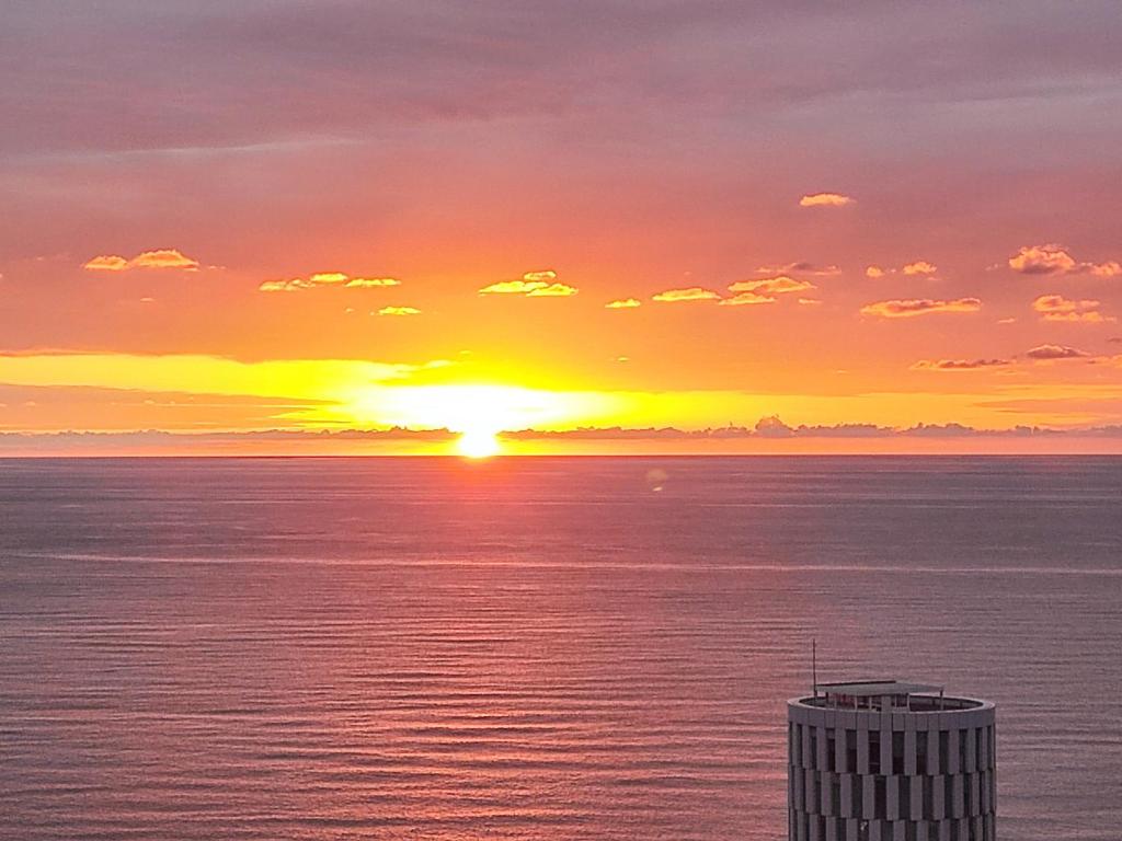 a sunset over the ocean with a building in the foreground at Intourist Residence in Batumi