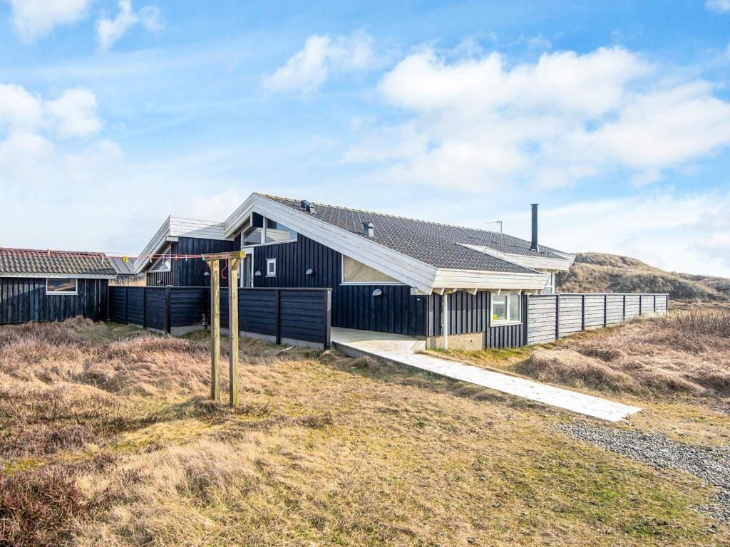 una casa negra en la cima de una colina en 9 person holiday home in Ringkøbing-By Traum, en Søndervig