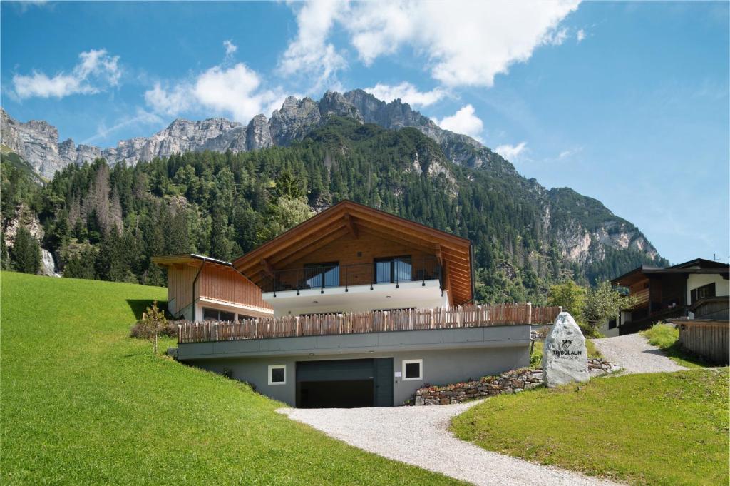a house on a hill with mountains in the background at Mountain Chalet Tribulaun Pflersch in Colle Isarco