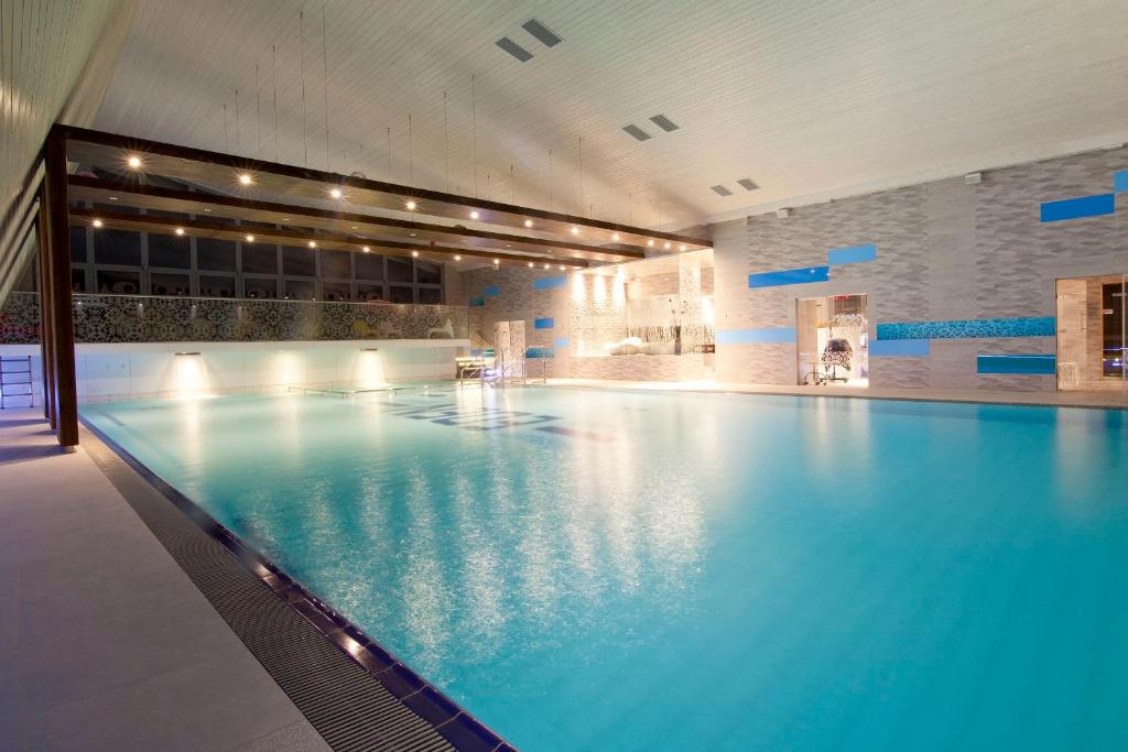 a large swimming pool with blue water in a building at Eden Resort & Spa in Mielno