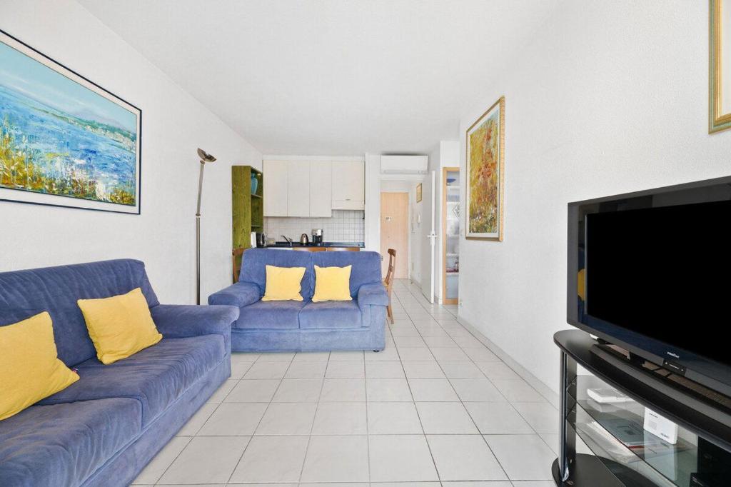 a living room with blue couches and a flat screen tv at RIVIERA PRESTIGE - Front de Mer - Terrasse - Parking in Roquebrune-Cap-Martin