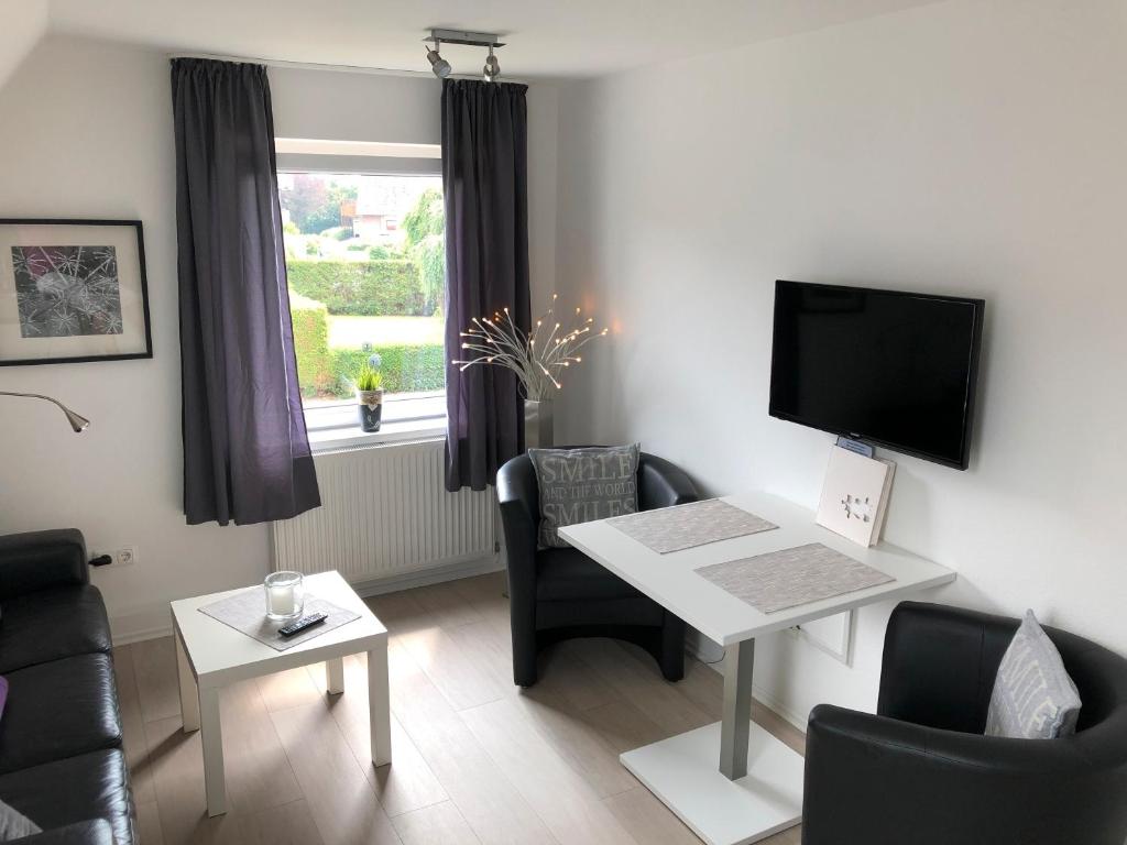 a living room with a tv and a table and chairs at Haus Lenchen mit Garten in Top Lage in Wangerland