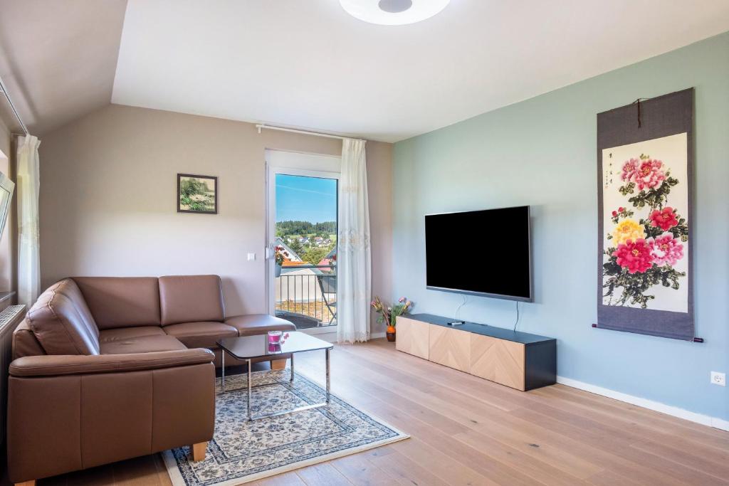 un salon avec un canapé et une télévision à écran plat dans l'établissement Haus Rosengarten, à Friedenweiler