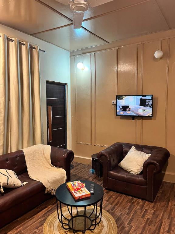 a living room with two leather couches and a tv at Prime Cottage 2bhk independent cottage home in Dimāpur