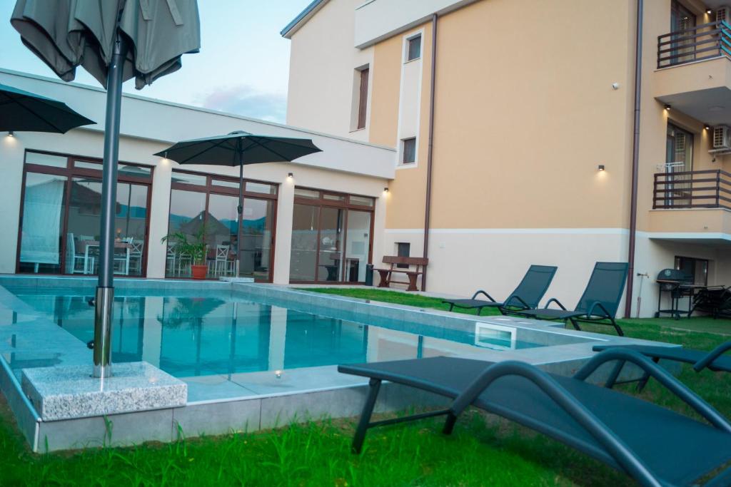 a swimming pool with chairs and umbrellas next to a building at Самуил къща за гости in Ognyanovo