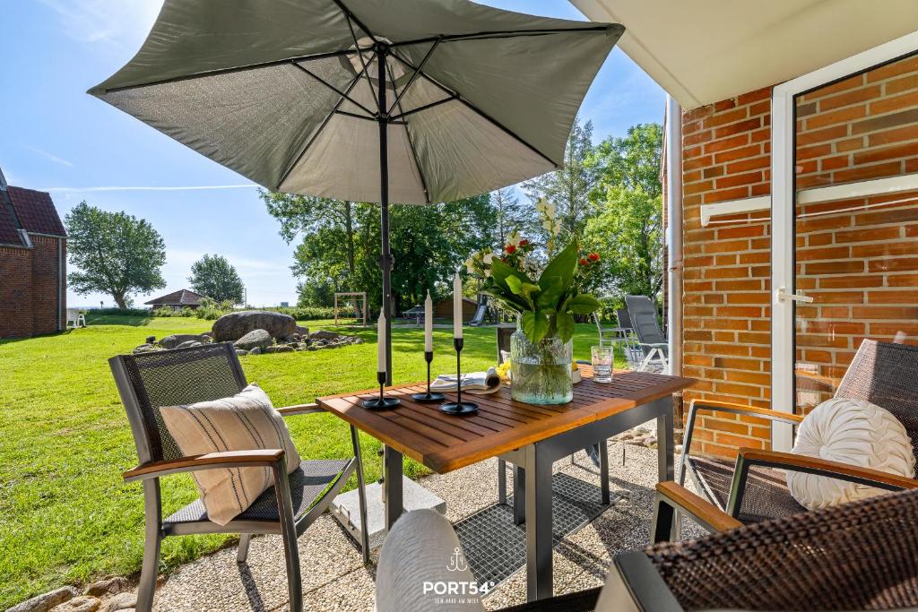 a table with an umbrella on a patio at Ferienwohnung Schmuckstück mit Meerblick Kronsgaard in Kronsgaard