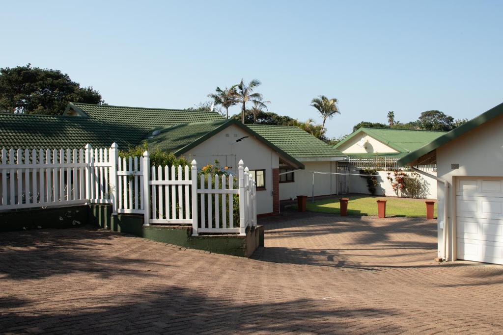 una cerca blanca frente a algunas casas en whales tail, en Port Shepstone
