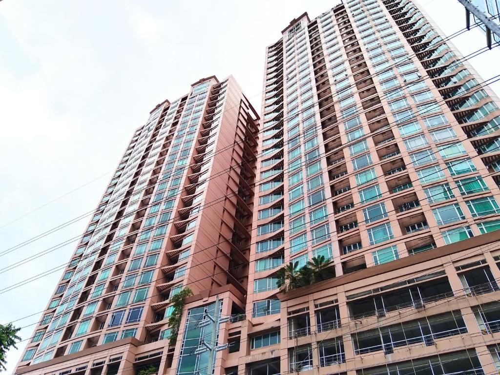 Un edificio alto con palmeras delante. en Monitor Gear Residences, en Manila