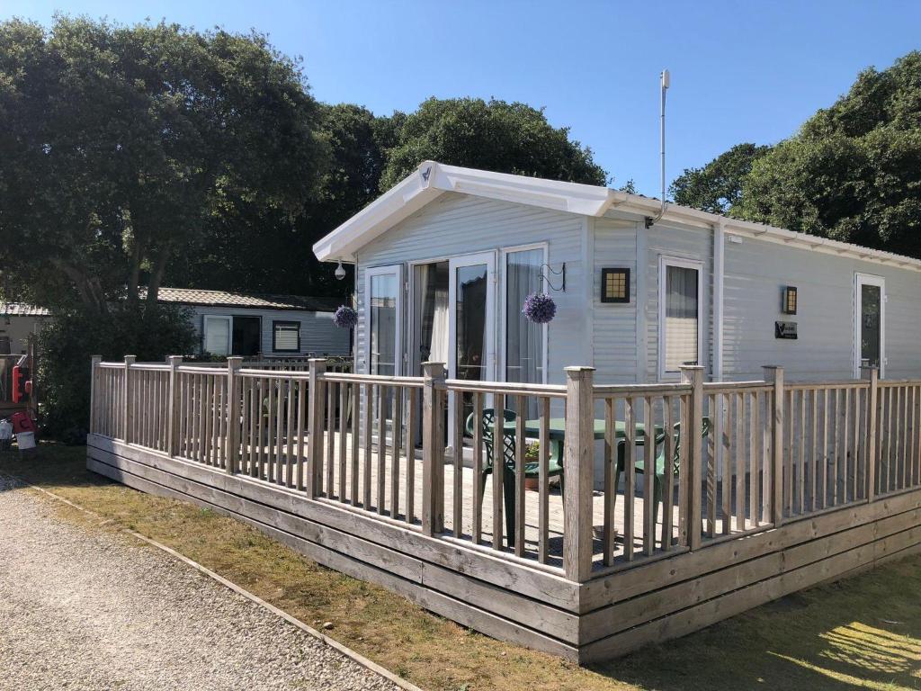 a small white house with a wooden fence at Beautiful Caravan With Decking At Azure Seas Ref 32060Az in Lowestoft