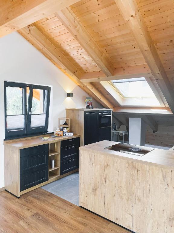 a kitchen with black appliances and a wooden ceiling at FeWo Leni - Modernes Apartment mit Bergblick - Zentral gelegen in Mittenwald