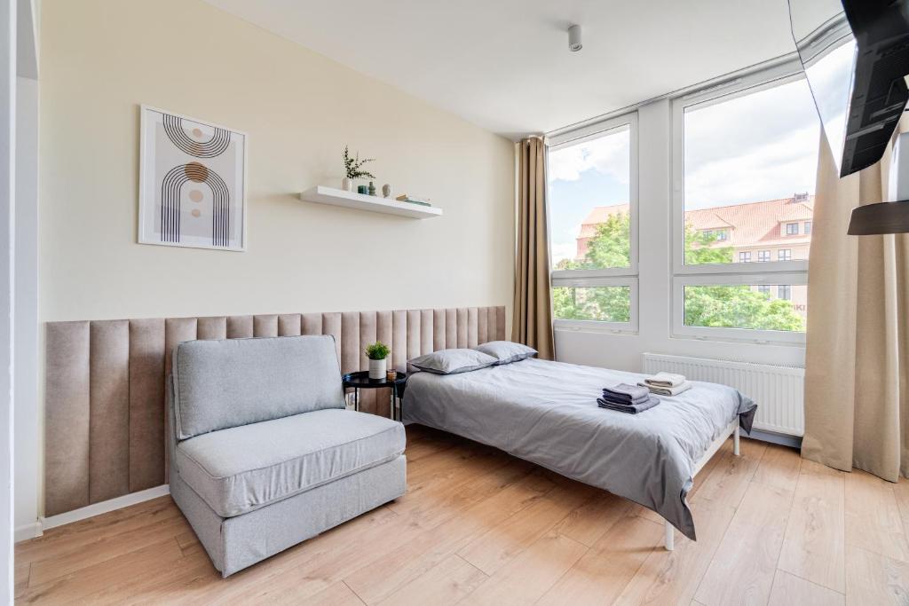 a bedroom with a bed and a chair and a window at COMFISTAY Apartamenty premium Katowicka 39 in Opole