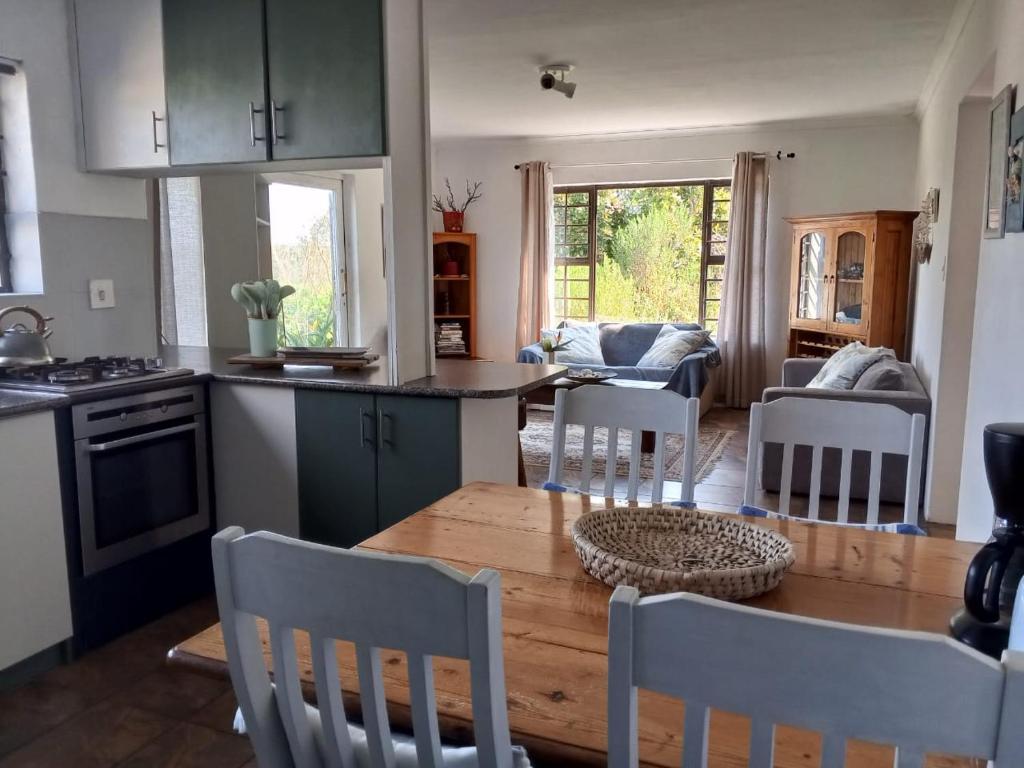 a kitchen and living room with a wooden table and chairs at Streams Cottage in Bettyʼs Bay