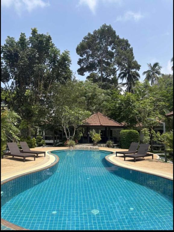 a swimming pool at a resort with chairs and trees at olivia village pool resort in Mae Nam