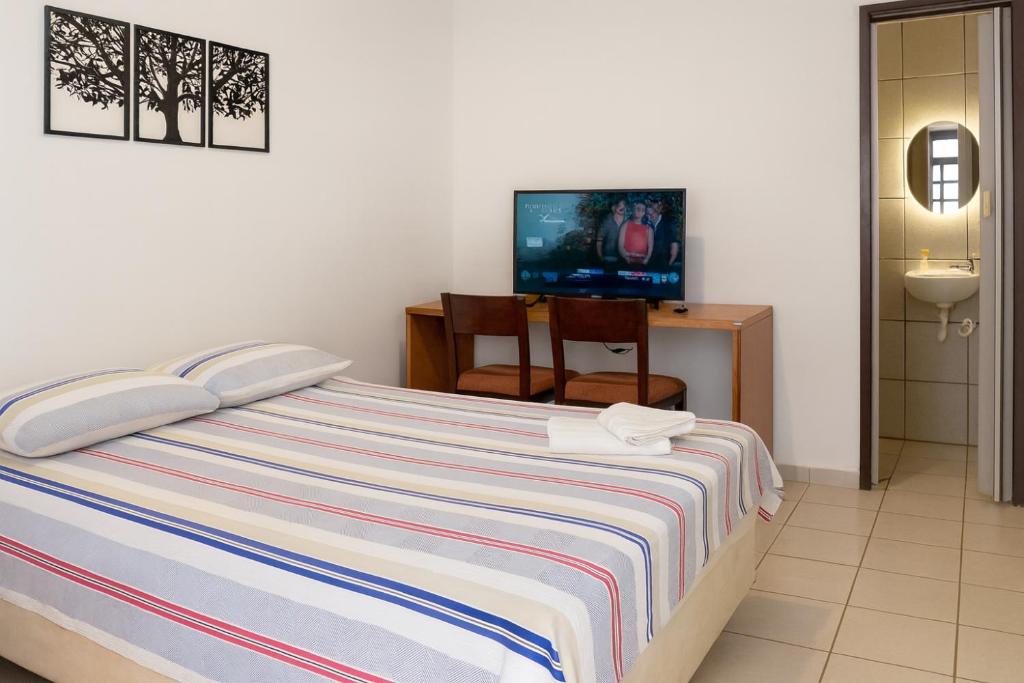 a bedroom with a bed with a television and a chair at Maestro in Fortaleza