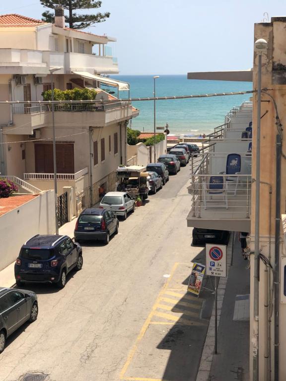a row of cars parked on a street next to the beach at Il Mare a Pochi Passi in Marina di Ragusa