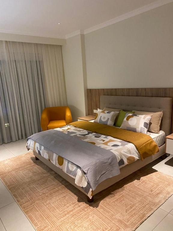 une chambre avec un grand lit et une chaise dans l'établissement ChristMindLimitedCompany, à Accra