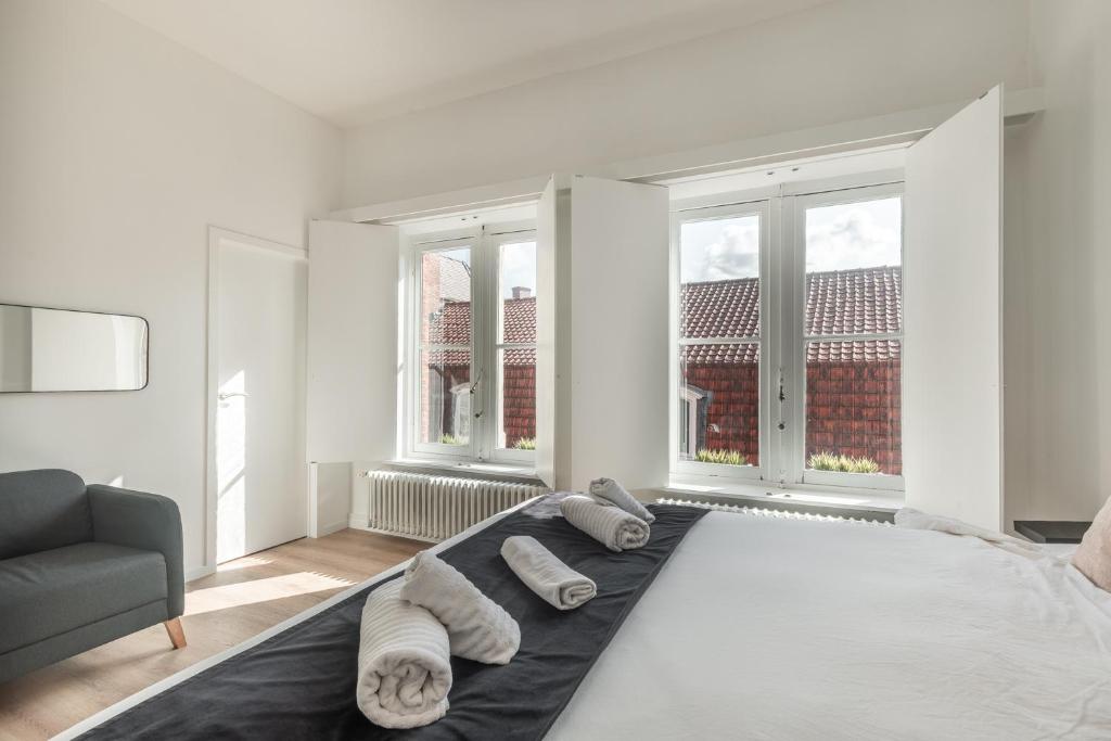 a white bedroom with a bed with towels on it at D28 Bruges in Bruges