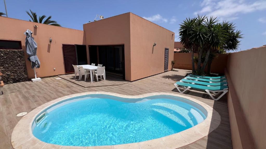 a large blue swimming pool in front of a house at Anahi Homes Corralejo - Villa Drago 12 in La Oliva