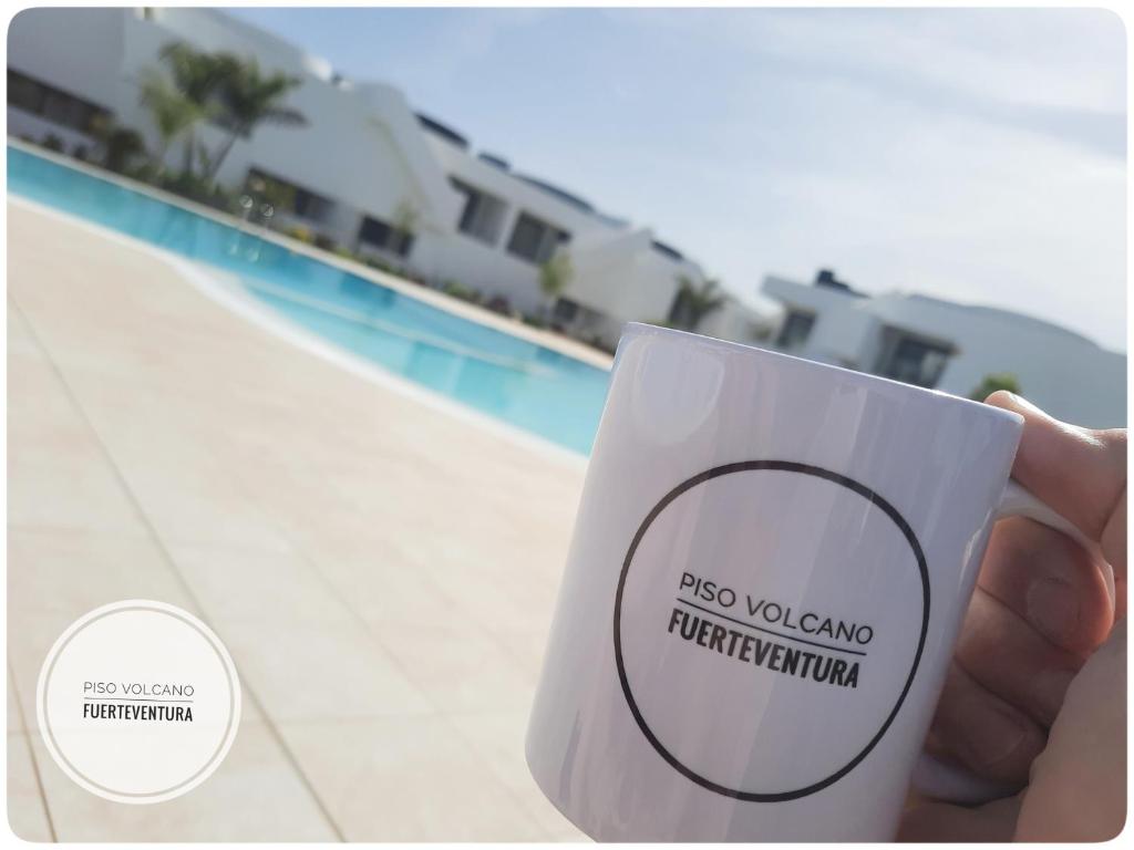 a hand holding a coffee cup next to a pool at Piso Volcano in Villaverde