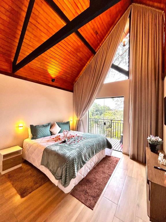 a bedroom with a bed and a large window at Charmê Chalés in Campos do Jordão