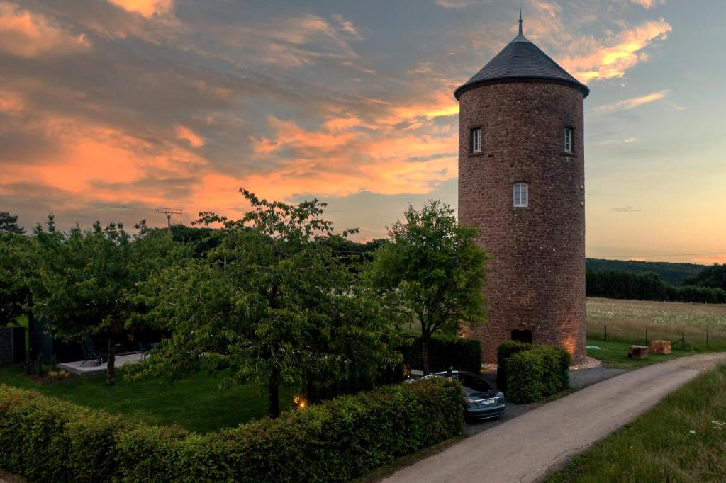 a brick tower with a car parked next to a road at EifelturmSuite in Utscheid