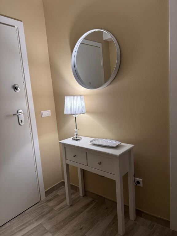 a room with a table with a lamp and a mirror at Apartamento con huerta in San Mamede de Carnota