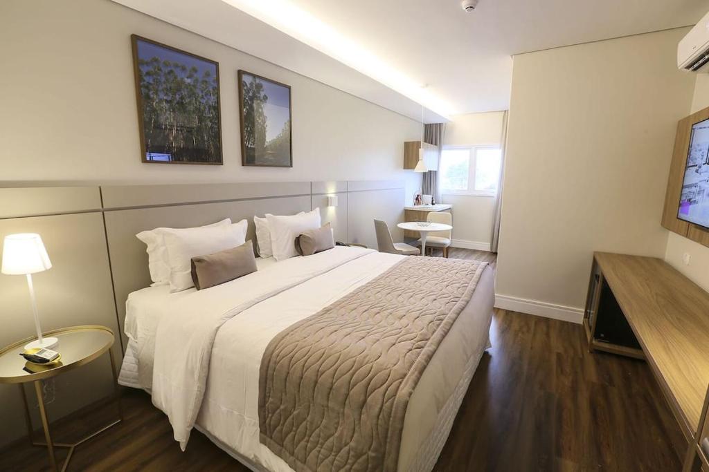 a hotel room with a large bed and a television at Hotel 4WOO in Telêmaco Borba