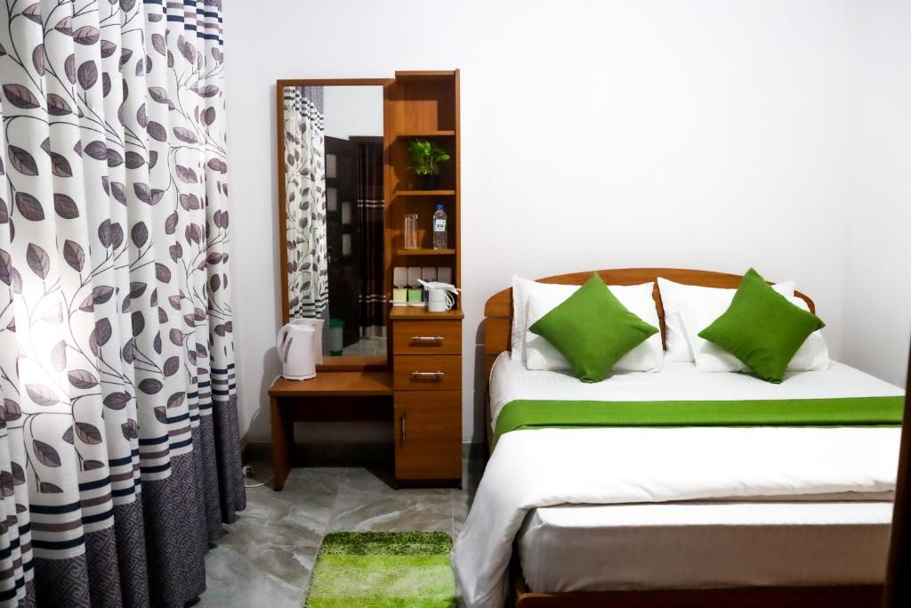 a bedroom with a bed with green pillows and a mirror at House Of Flowers in Ella
