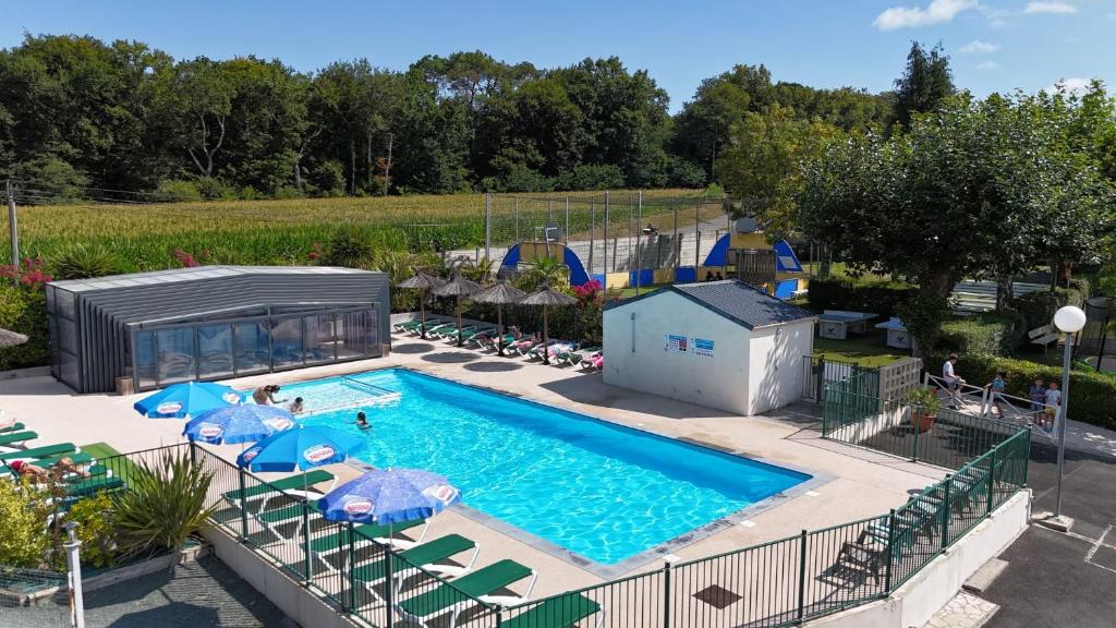 a pool with chairs and umbrellas in a resort at Camping Le Ruisseau in Saint-André-de-Seignanx