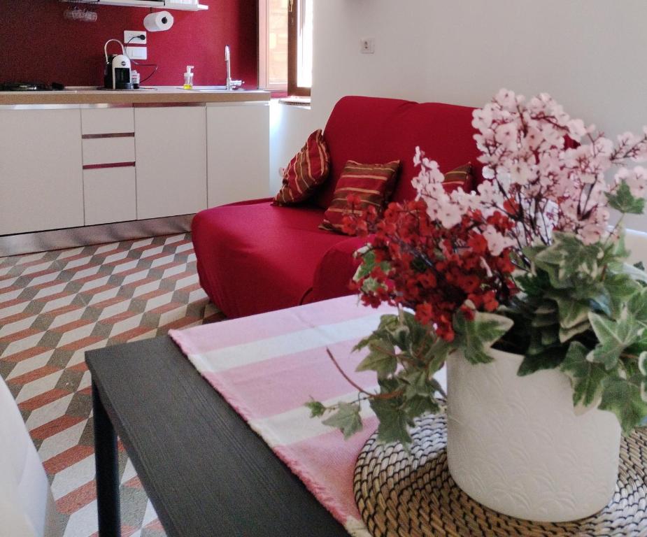 a living room with a red couch and a vase with flowers at A casa mia in Santa Maria degli Angeli