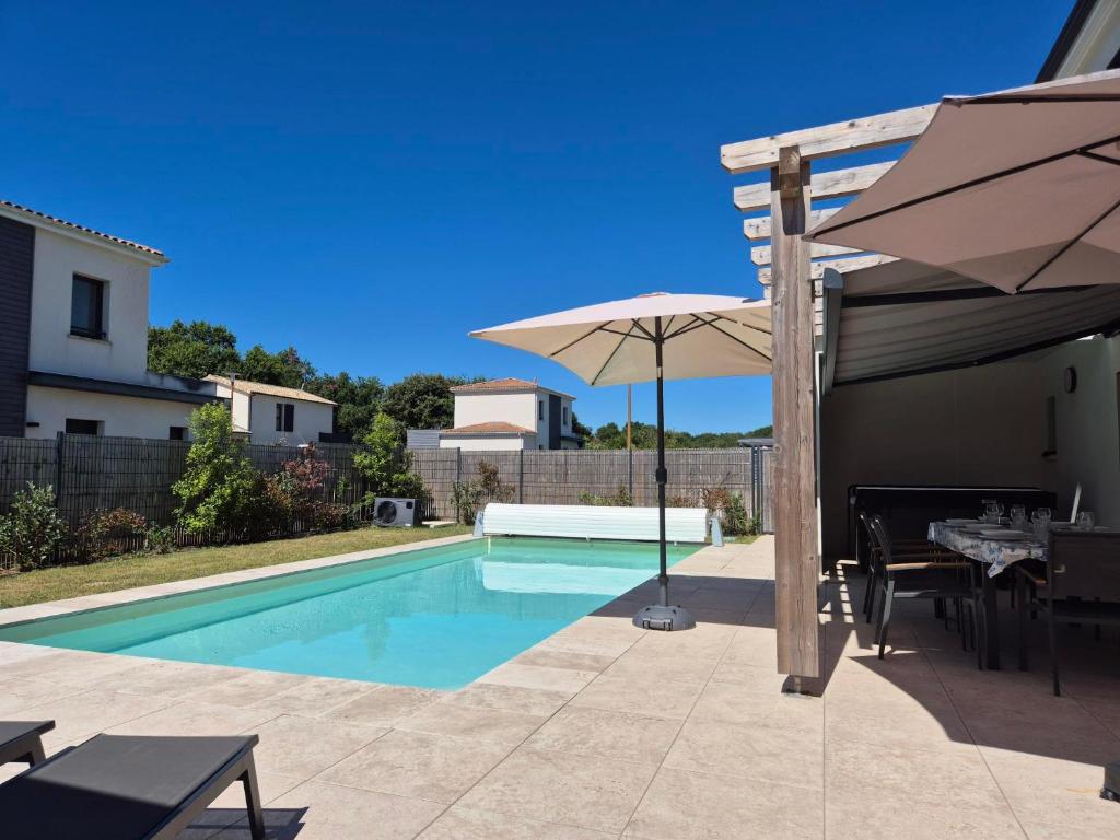 a swimming pool with an umbrella and a table and chairs at La Forêt d'Armotte villa 14 in Saint-Augustin