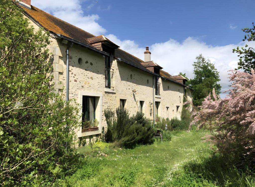 una vecchia casa in pietra con un prato davanti di Appartement à l'Aujardière a Durtal