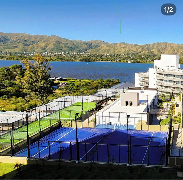 a tennis court next to a body of water at Veneto Village in Villa Parque Siquiman