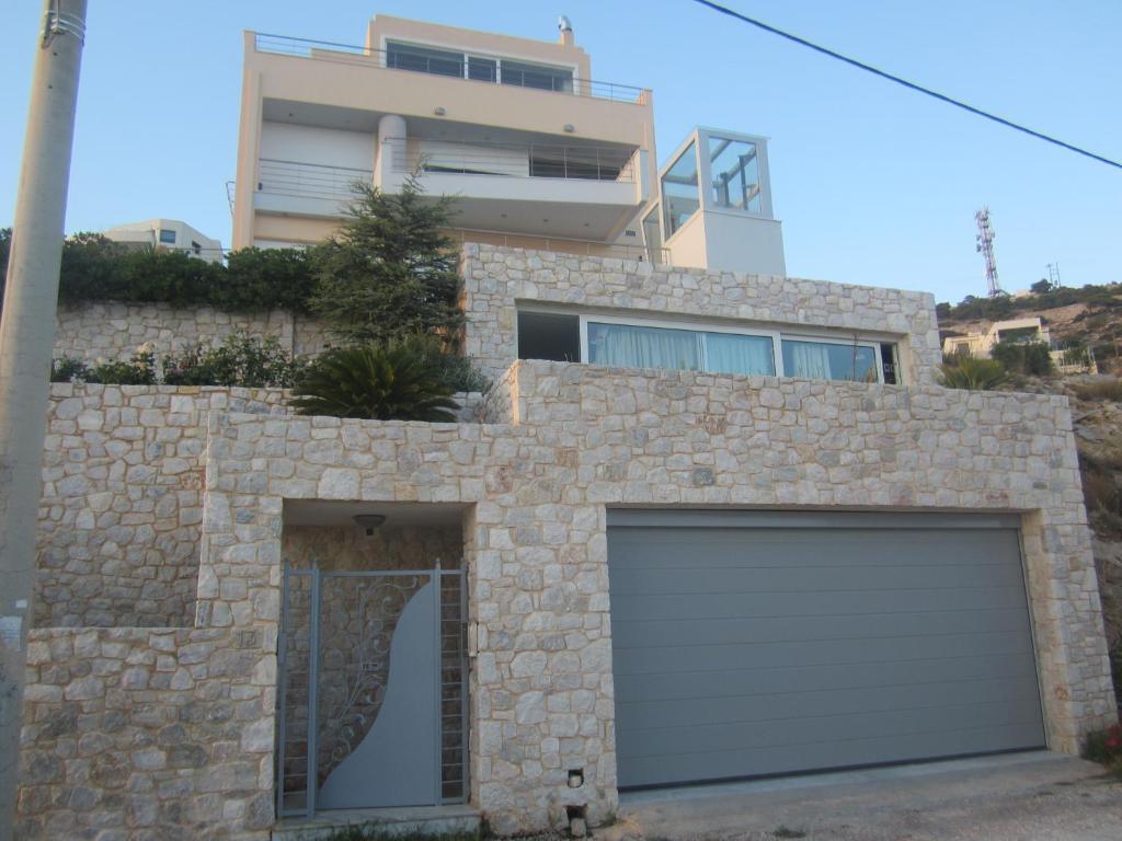 a house with a garage with a building in the background at Viva B&B in Anavyssos