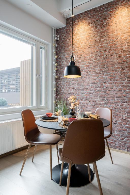 a dining room with a brick wall and a table and chairs at City Home Alvari, jäähdytys, ilmainen pysäköinti autohallissa in Kuopio