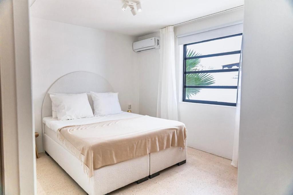 een witte slaapkamer met een bed en een raam bij Nusa B in Jan Thiel